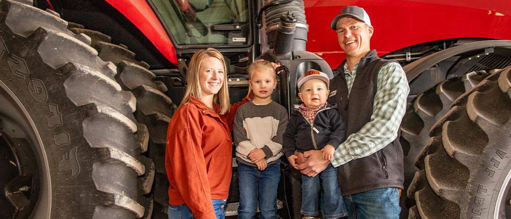 Family of four next to tractor